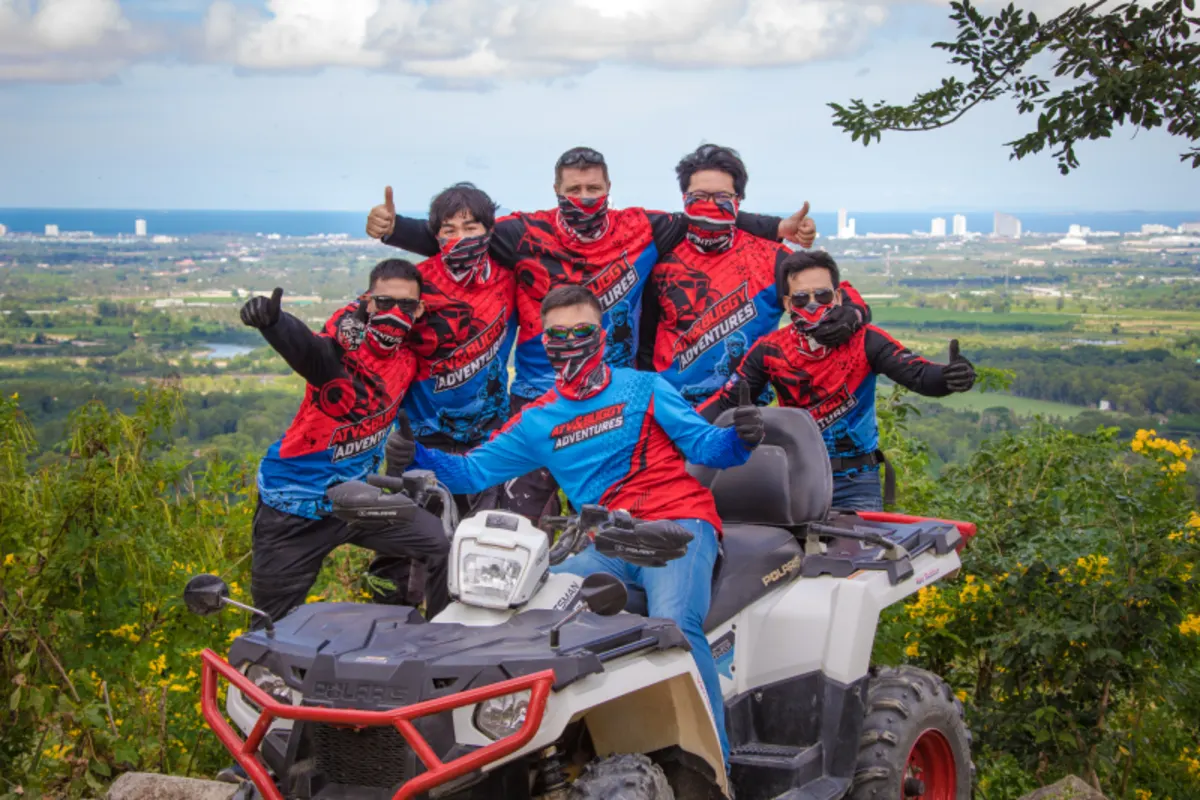 Team of riders giving thumbs up at hilltop viewpoint overlooking Pattaya