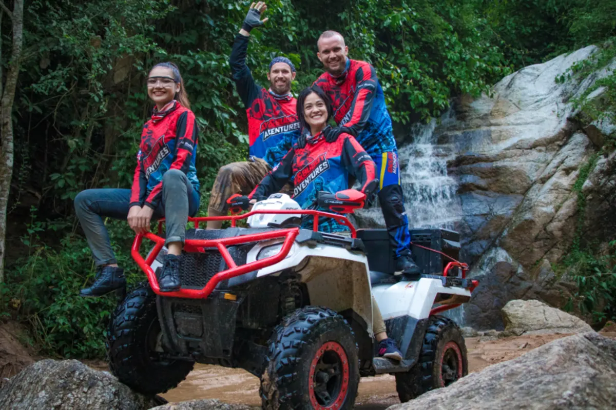Group posing with ATV at waterfall stop in the jungle